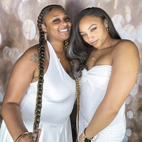 two women wearing white dresses smiling and posing at all white party photo booth in Carson California