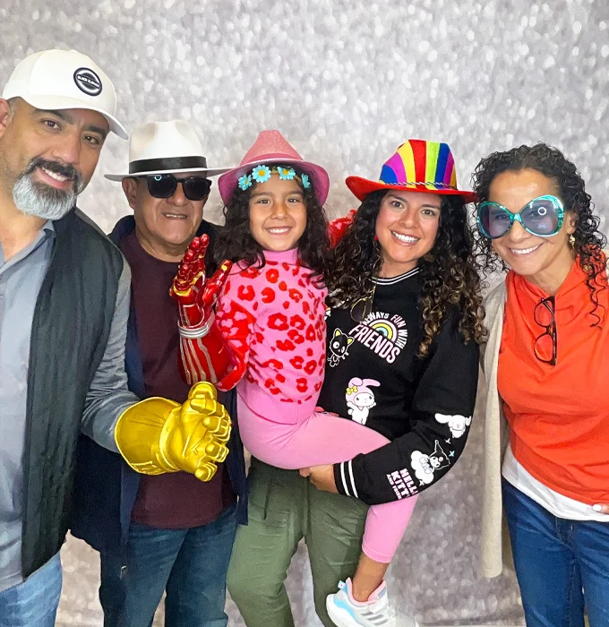 family group wearing silly hats and oversized glasses posing at photo booth in Carson California