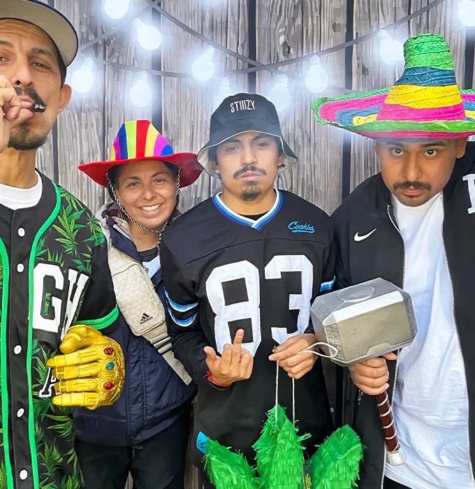 group of friends wearing colorful hats and holding thor hammer photo booth prop in Carson California