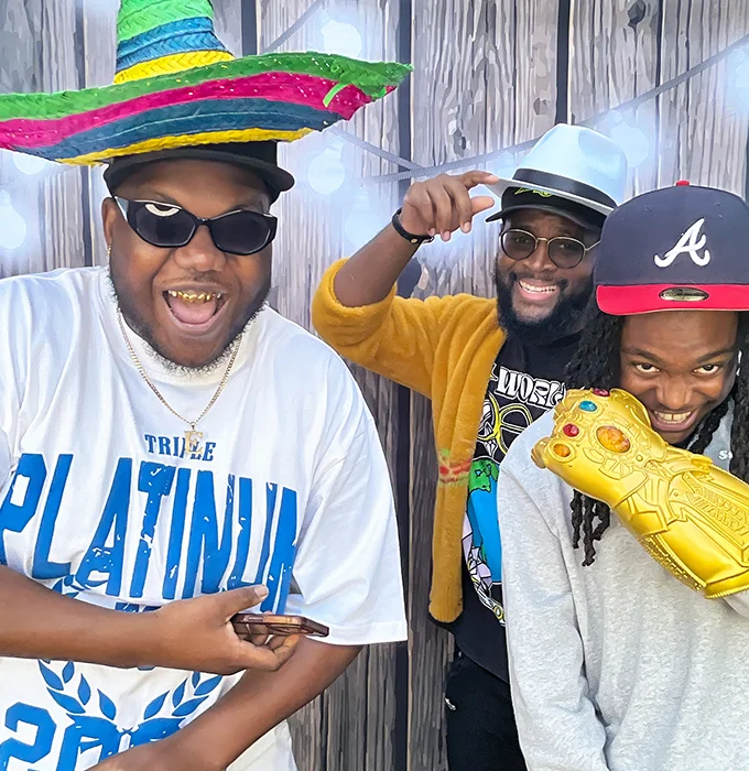 friends posing with colorful sombrero and thanos glove props at photo booth in Carson California