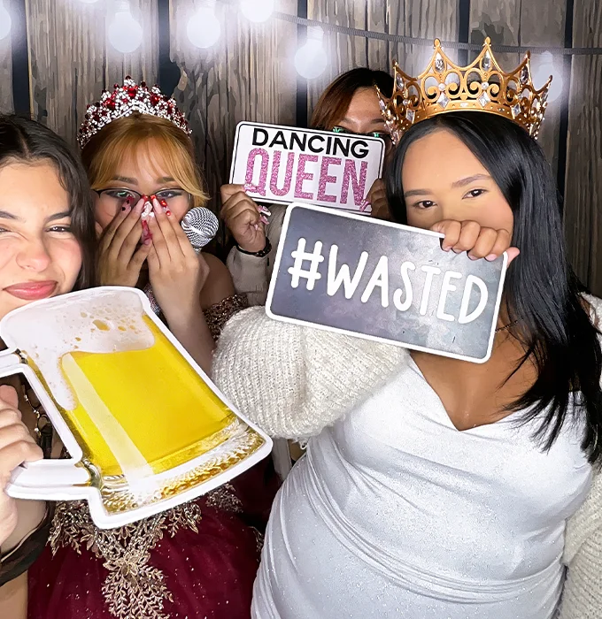 young women holding funny party signs and props at photo booth in Carson California