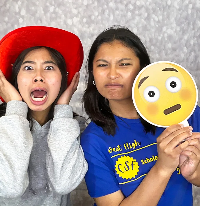 friends posing with emoji prop at photo booth in Carson California